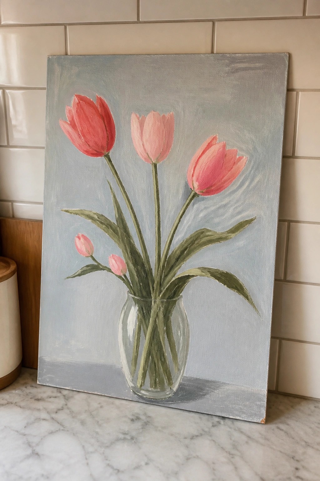 Painting of pink tulips in glass vase on marble countertop against tiled wall