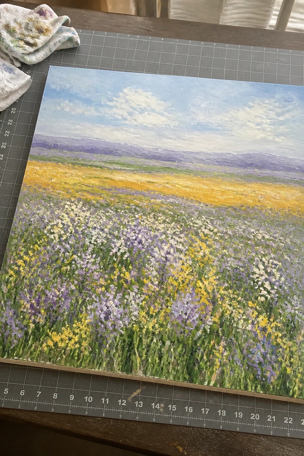 Vivid painting of colorful wildflower meadow on gray cutting mat with paint rag
