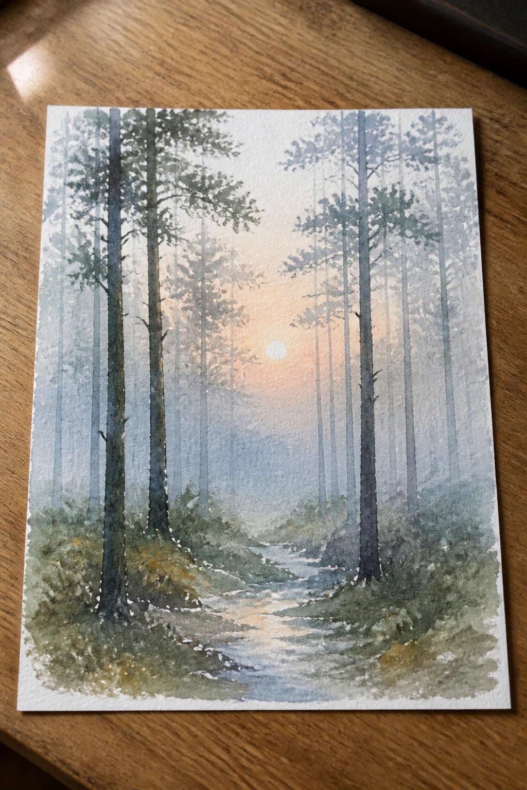 Watercolor painting of misty pine forest with winding path and glowing sunset.