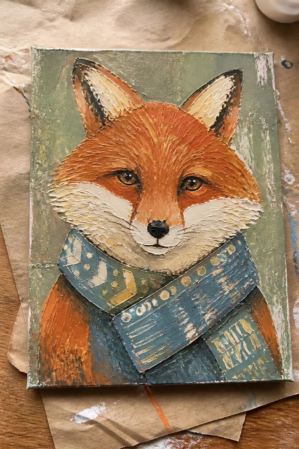 Impasto painting of orange fox with white muzzle wearing blue patterned scarf.