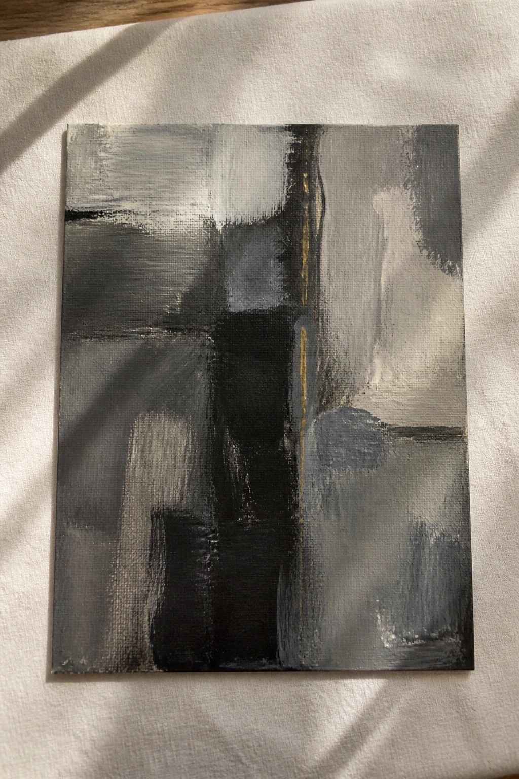 Abstract grayscale painting with bold black shapes and gold accents on canvas