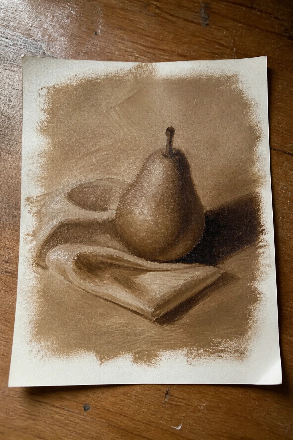 Brown-toned still life drawing of a pear on draped fabric with shadows.