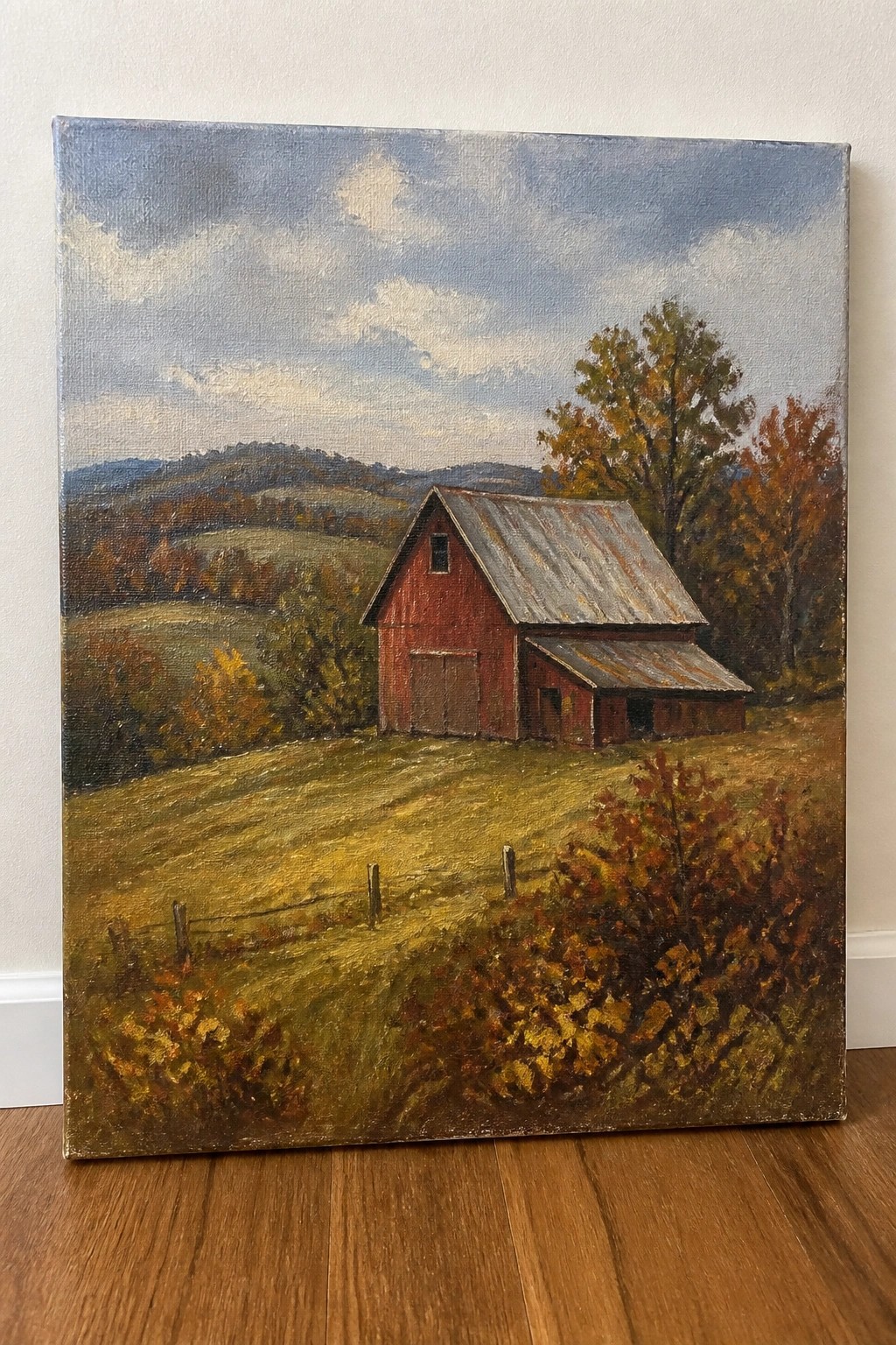 Red barn with metal roof amid autumn hills, trees, and grassy field