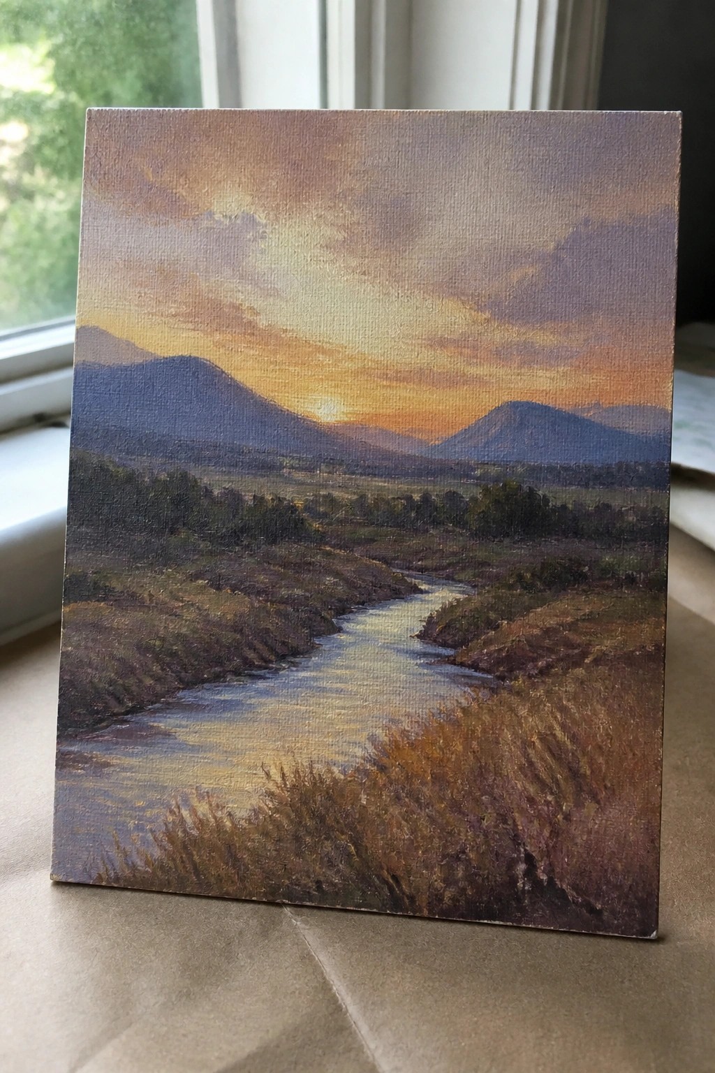 Oil painting of winding river through hills under vibrant orange-purple sunset sky.