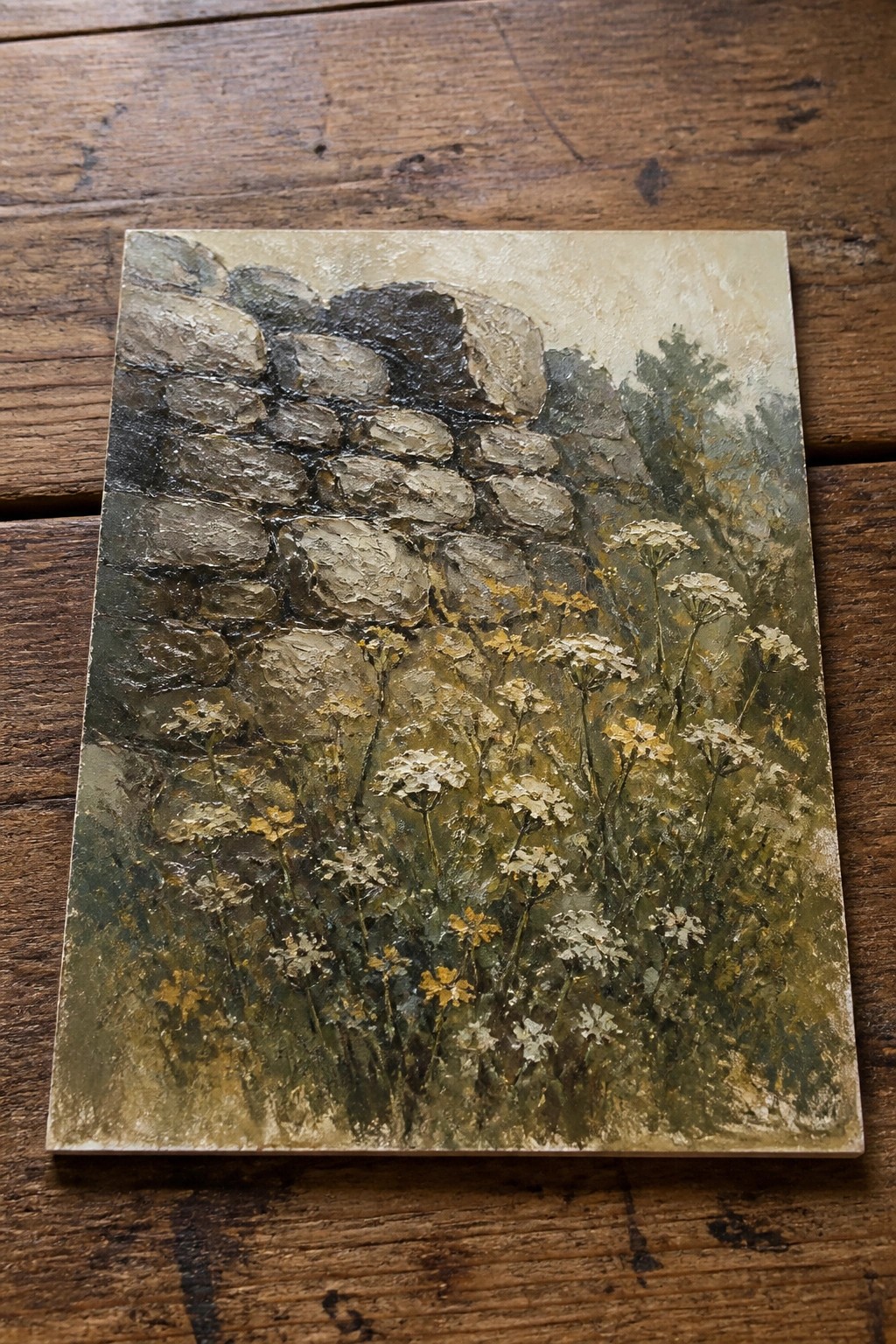 Oil painting of a rough stone wall with white wildflowers growing in front of it.