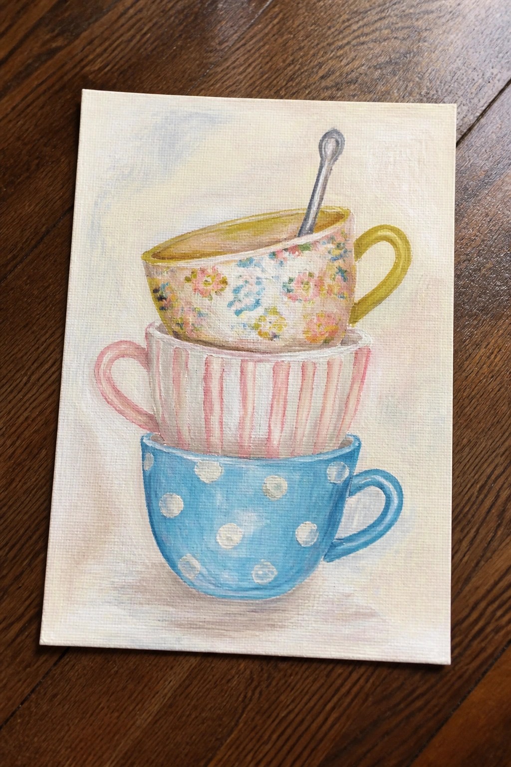 Three stacked teacups in blue polka dots, pink stripes, and floral pattern with spoon.