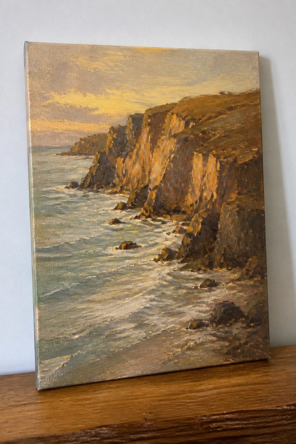 Oil painting of golden sunset over rugged cliffs with waves crashing on shore