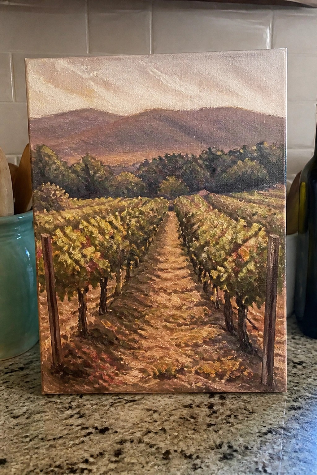 Painting of vineyard rows with autumn grapevines leading toward distant mountains on canvas.