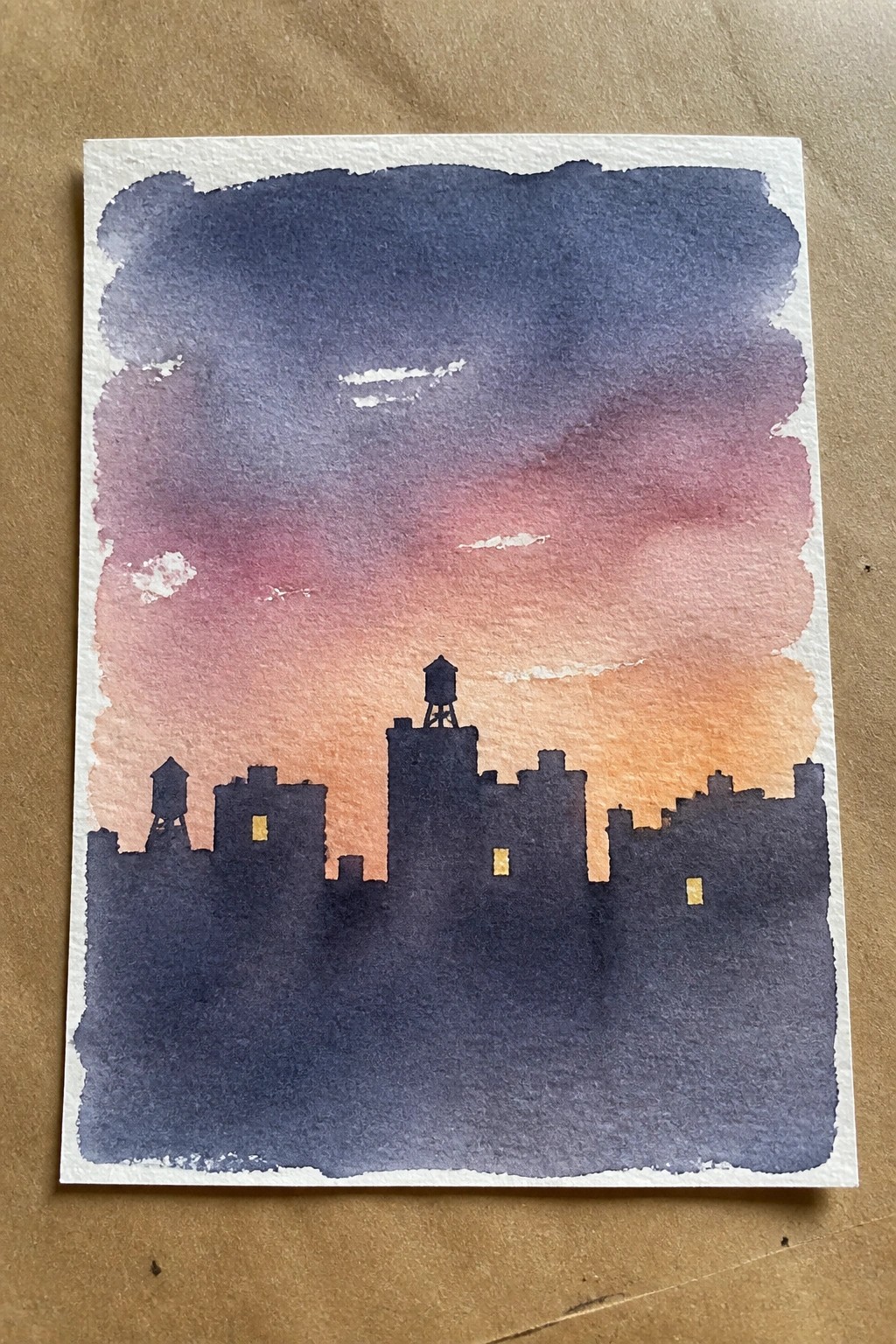 Watercolor city skyline silhouette with water tower against purple pink orange sunset sky and lit windows