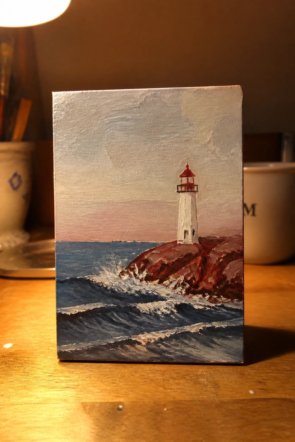 Miniature painting of white lighthouse on rocky cliff with crashing waves and pink sky