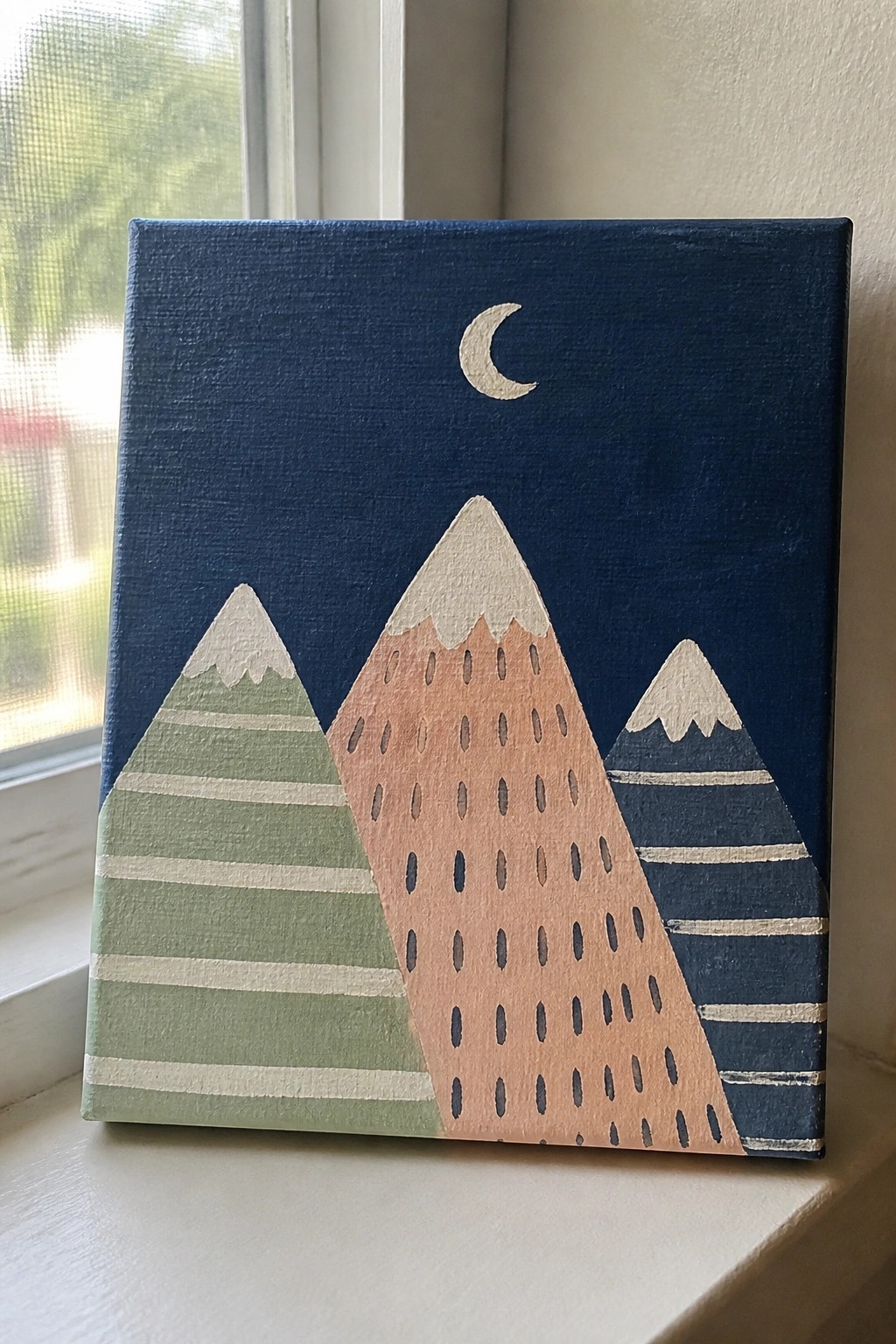 Canvas painting of green, peach, and blue striped mountains under a crescent moon.