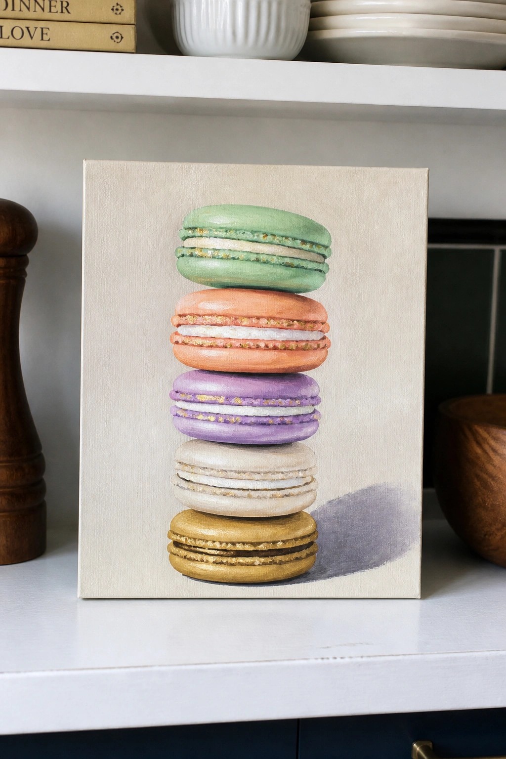 Stacked pastel macarons in green, orange, purple, beige, and gold on canvas