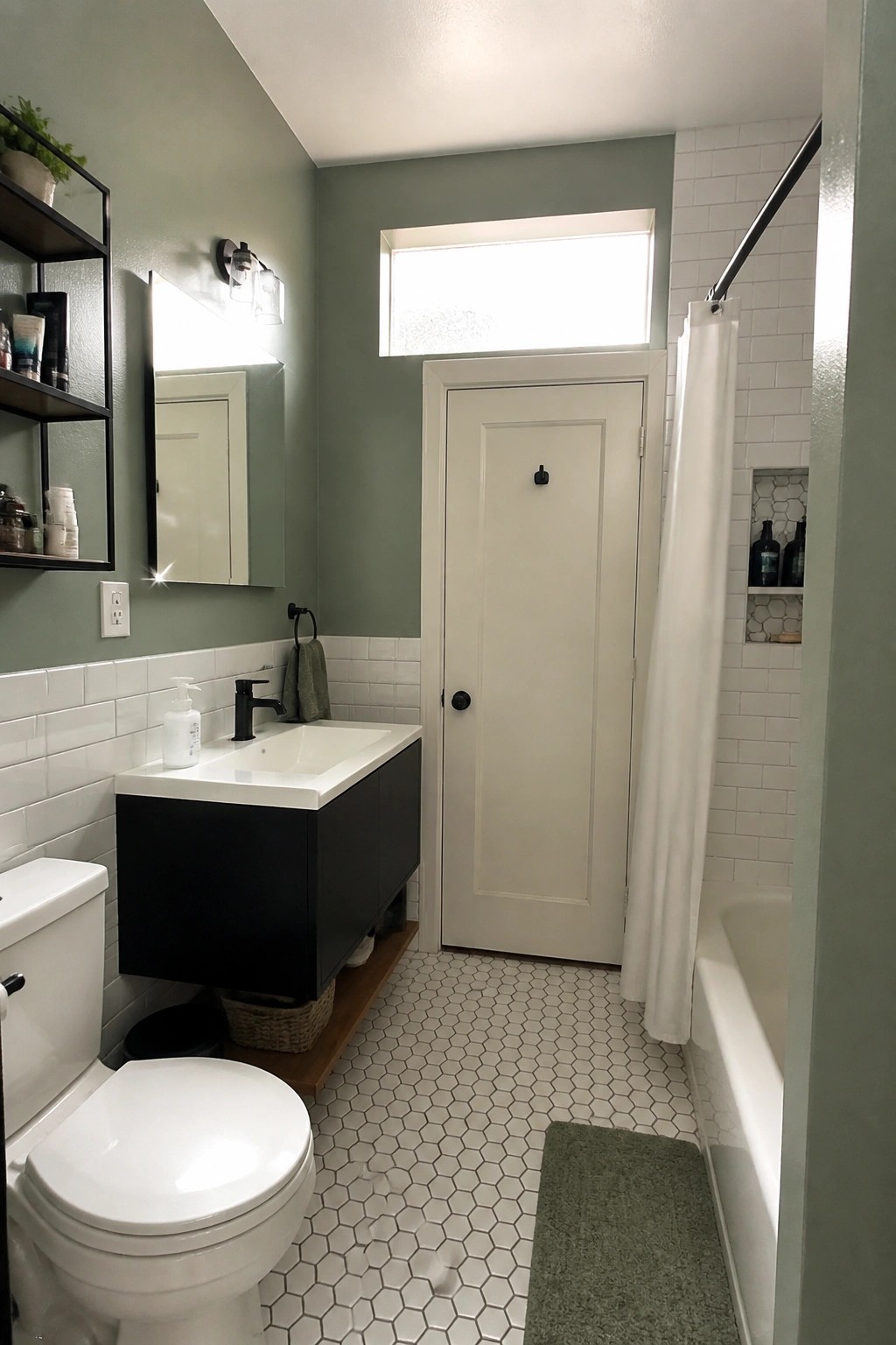 A bathroom with soft sage green walls above white subway tile.