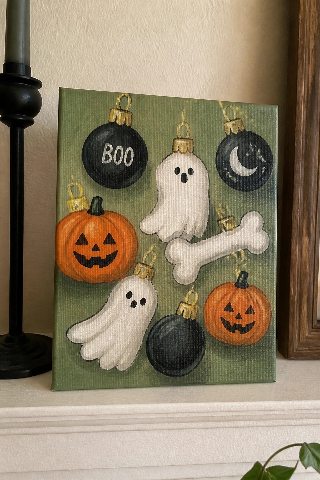 Halloween painting with ghosts, pumpkins, black ornaments, and bone on green canvas