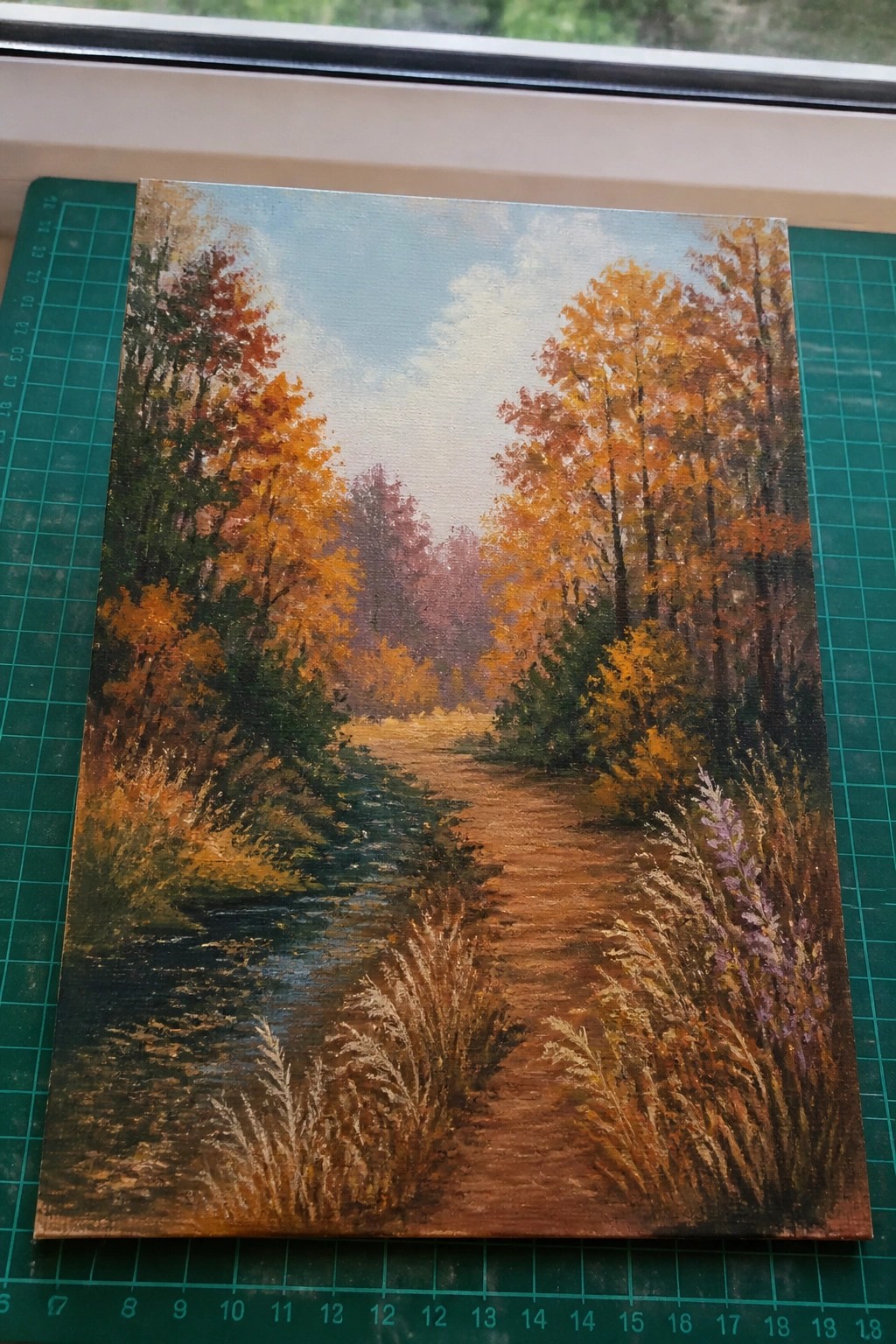 Autumn forest painting with orange trees, dirt path, stream on green mat
