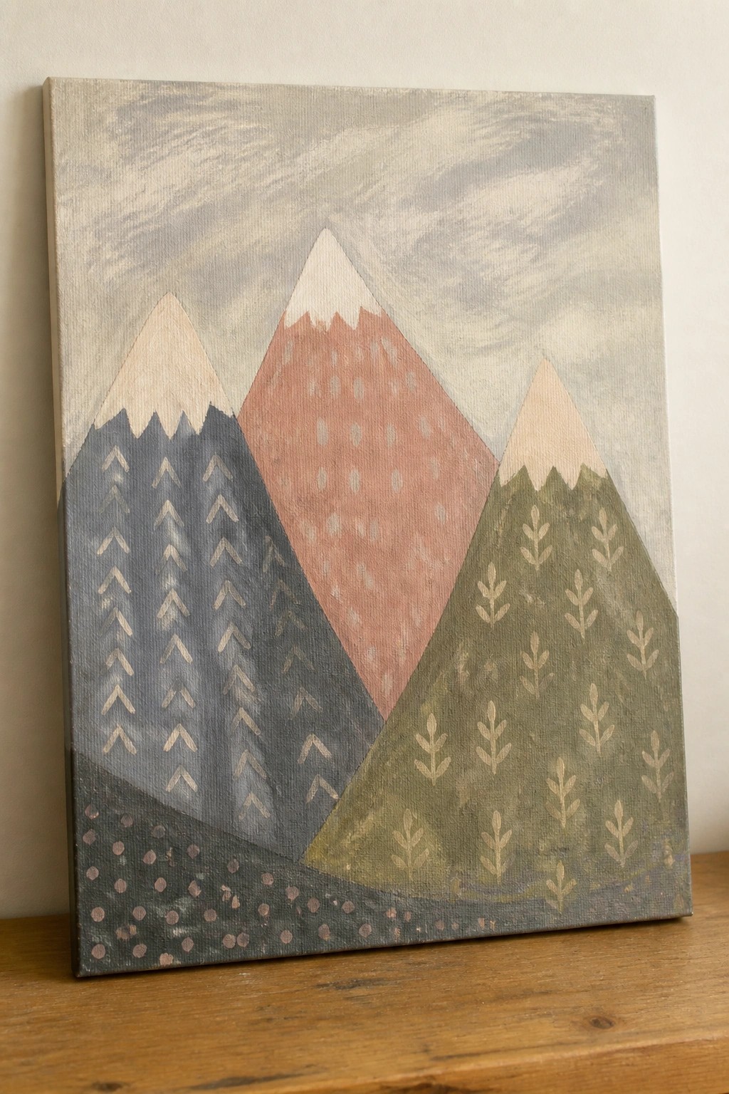 Abstract canvas painting of stylized mountains with patterned slopes in soft colors