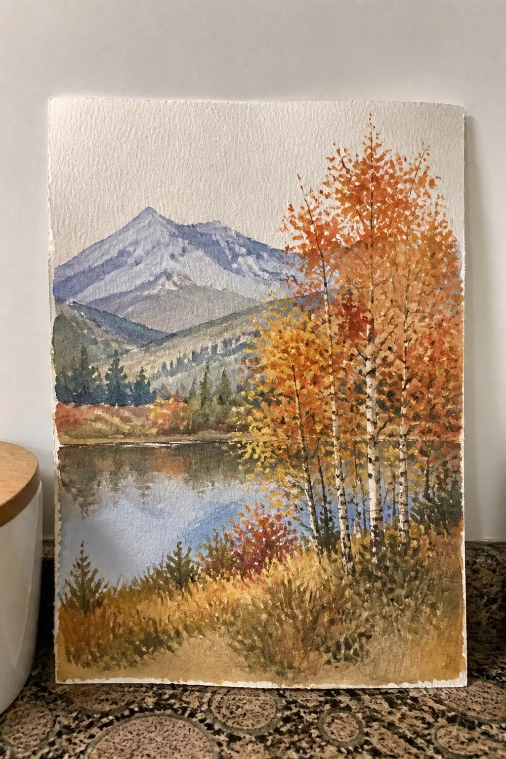 Watercolor landscape of autumn trees with white trunks beside a reflective mountain lake