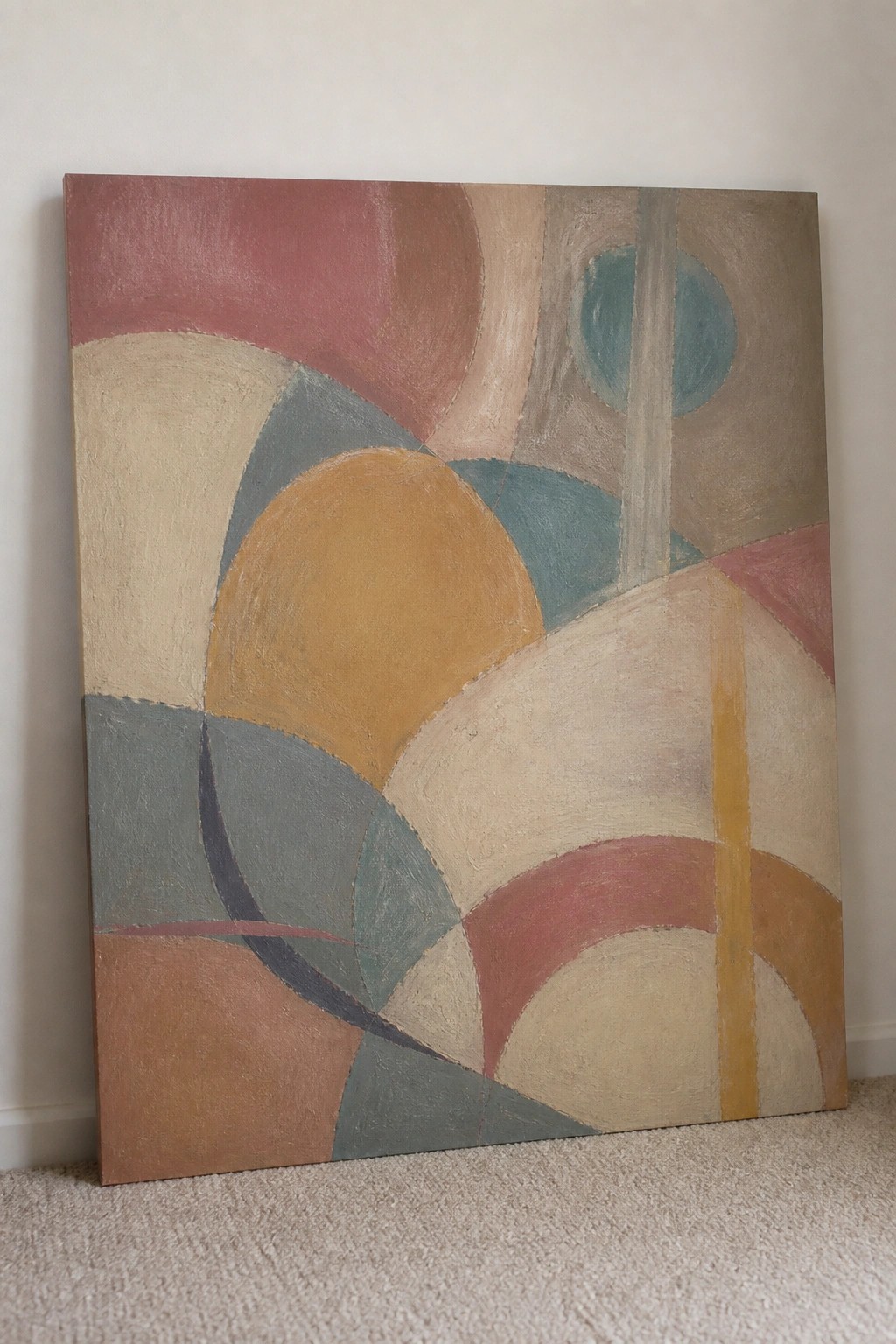Large abstract painting with overlapping curved shapes in muted red, blue, yellow and beige tones on carpet