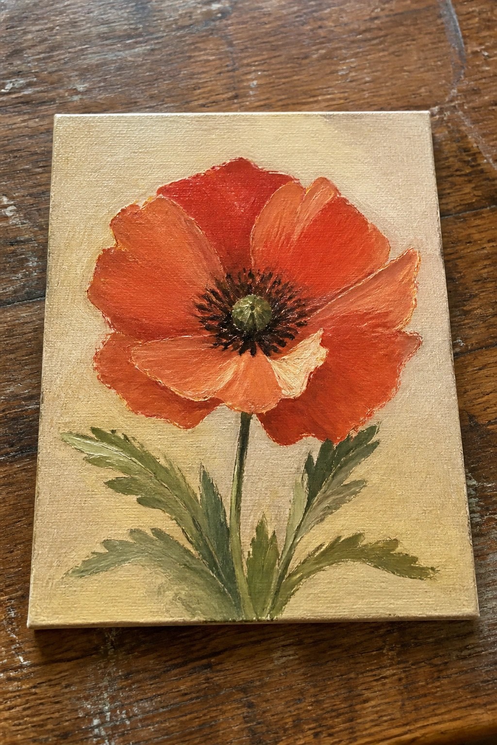 Vibrant red poppy with dark center and green leaves on beige canvas.