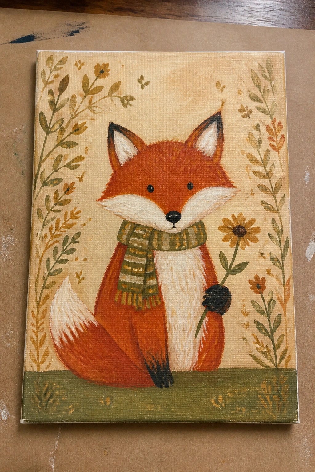 Folk-art fox in green scarf holds yellow flower amid leafy borders on canvas