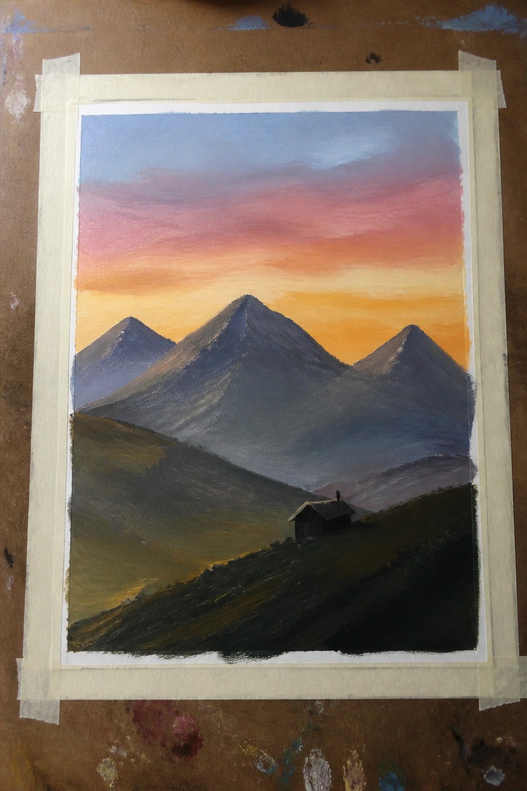 Mountain landscape painting with cabin under pink-orange sunset sky and misty peaks