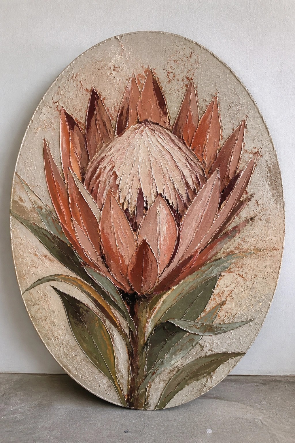 Textured oval relief of a blooming protea with copper petals and green leaves.