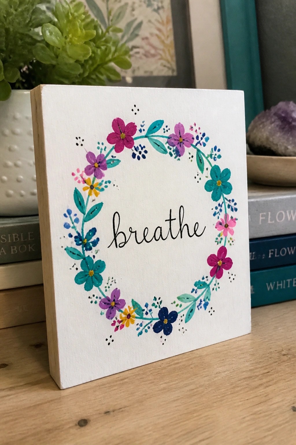 Small white canvas with colorful floral wreath and black 