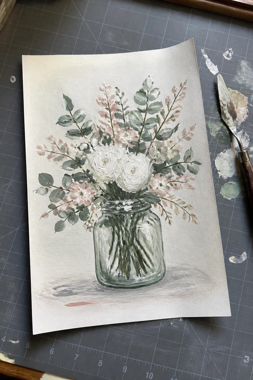 Watercolor painting of white and pink flowers in a glass mason jar on a mat