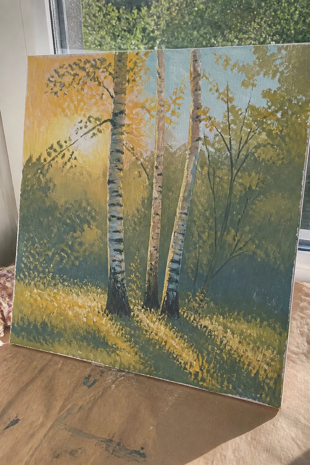 A painting of birch trees with light bark in a green forest, sunlight glowing from the left side.