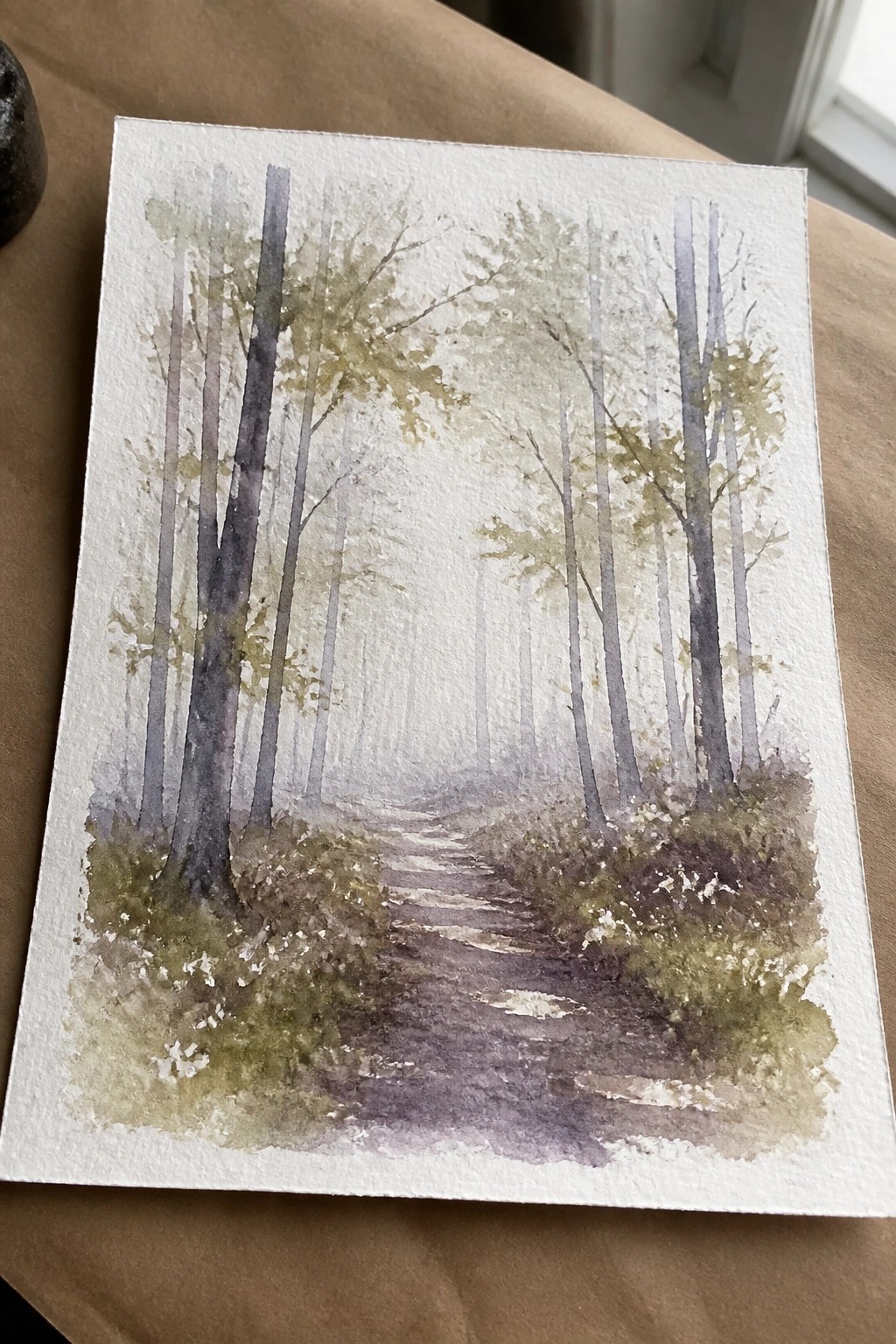 Watercolor painting of misty path winding through tall trees in forest