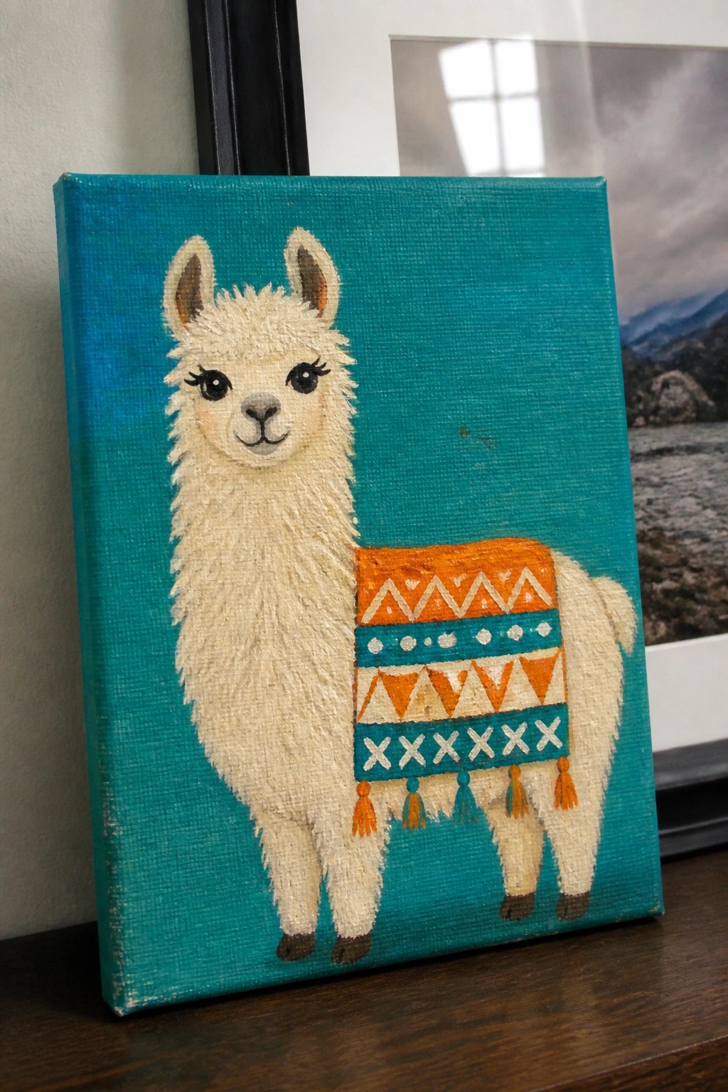 White llama with colorful patterned blanket on teal canvas painting