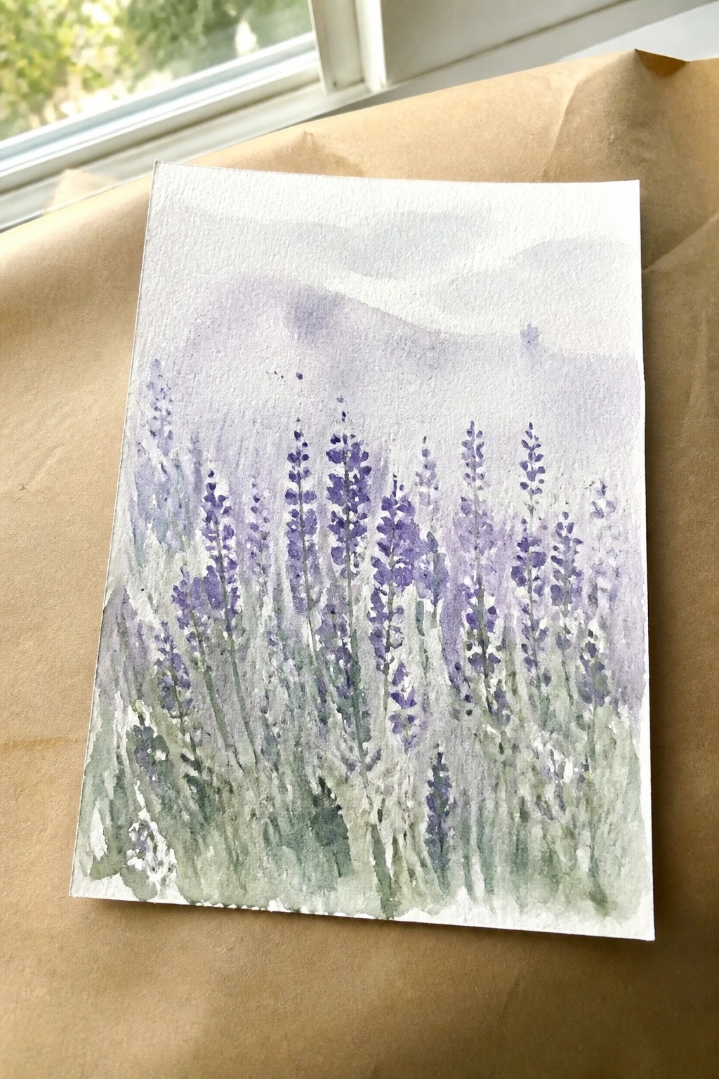 Watercolor painting of purple wildflowers with green stems on white paper
