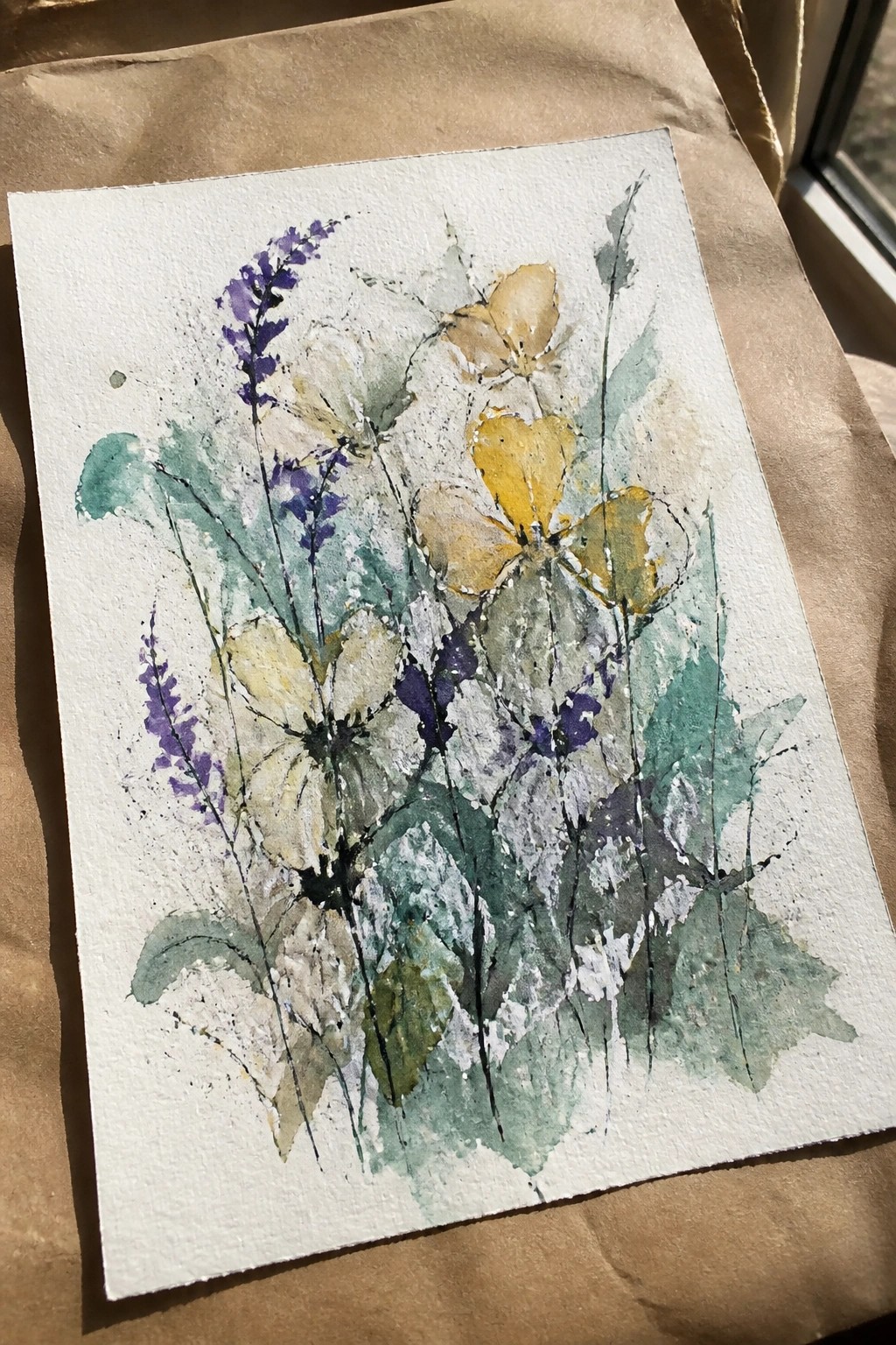 Watercolor wildflowers in purple, yellow, and green hues on textured white paper