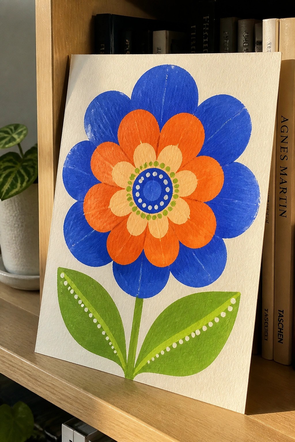 Colorful hand-painted flower with blue petals, orange center, and green leaves