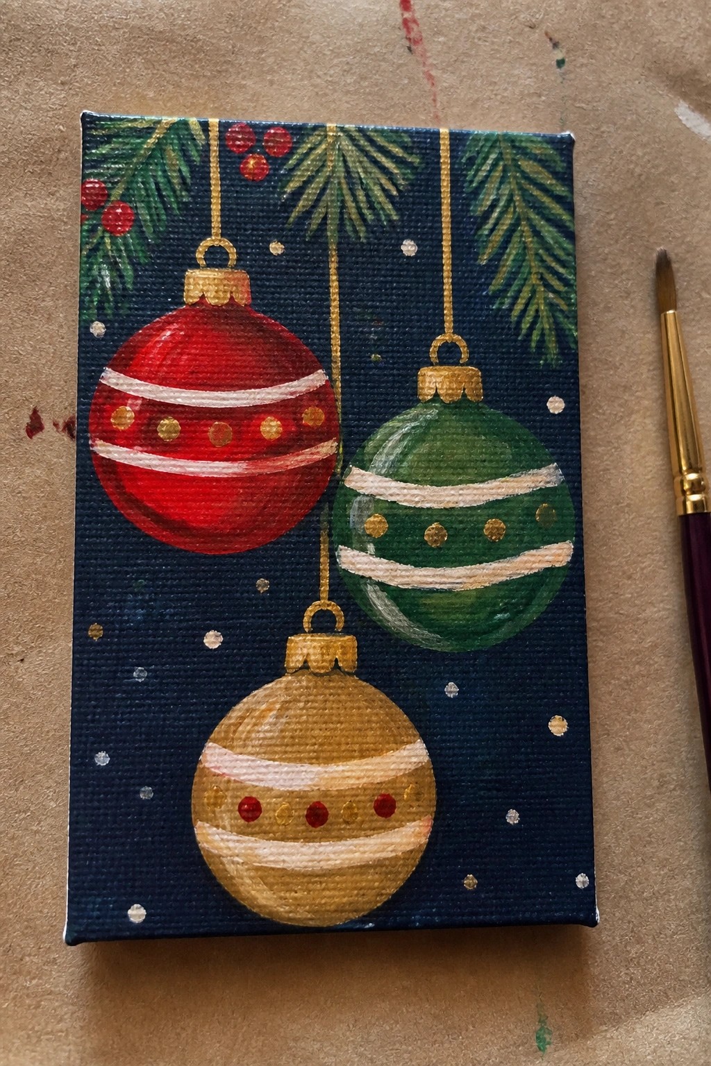 Acrylic painting of red, green, and gold Christmas ornaments on dark blue canvas
