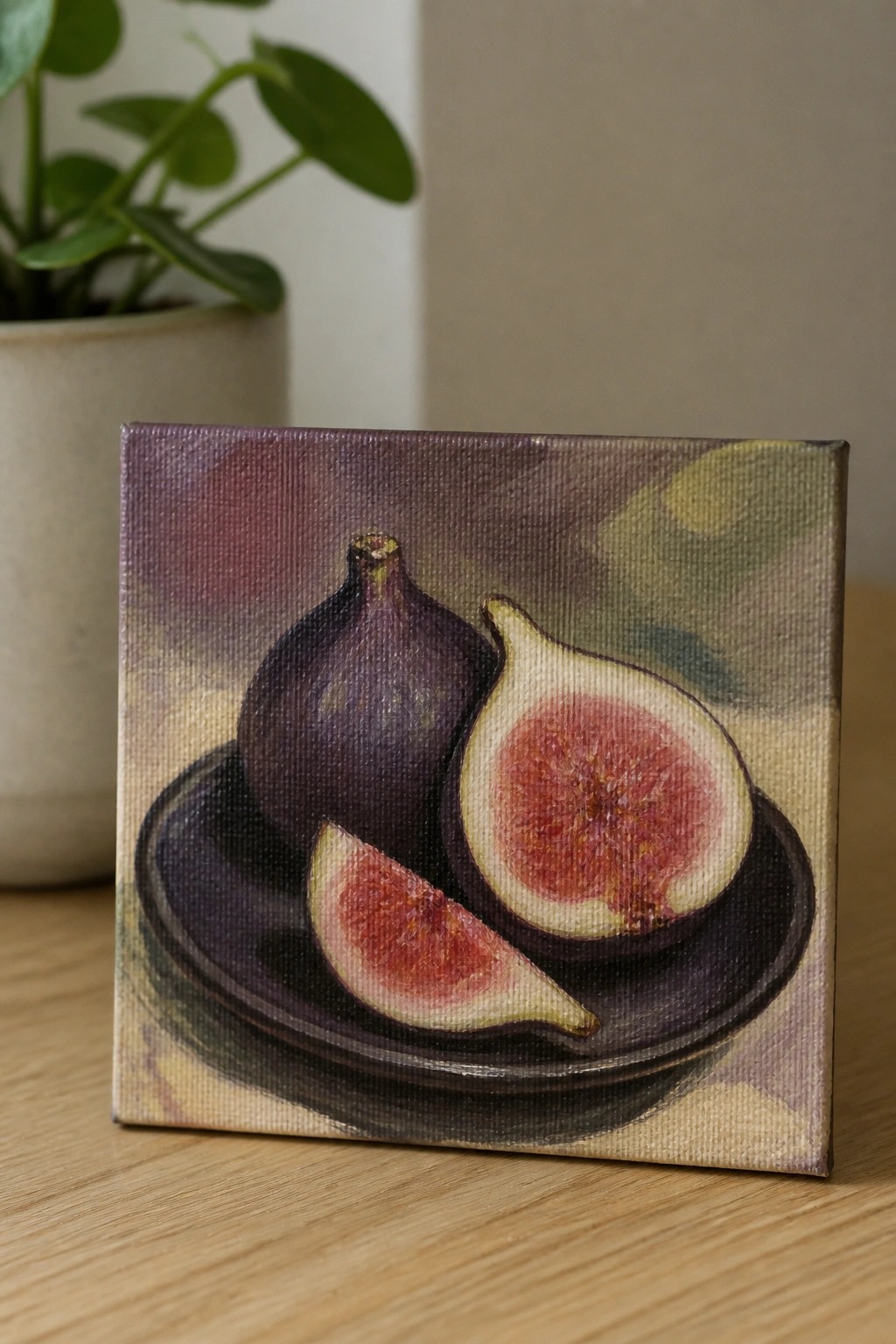 Small canvas painting of whole and sliced figs on a dark plate