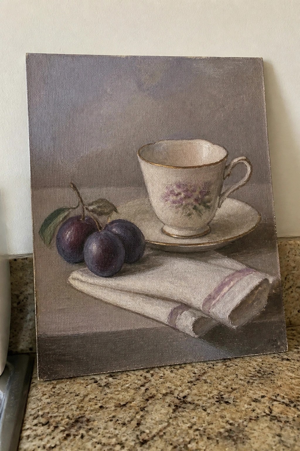 Realistic still life with purple plums, floral teacup on saucer, and striped napkin.