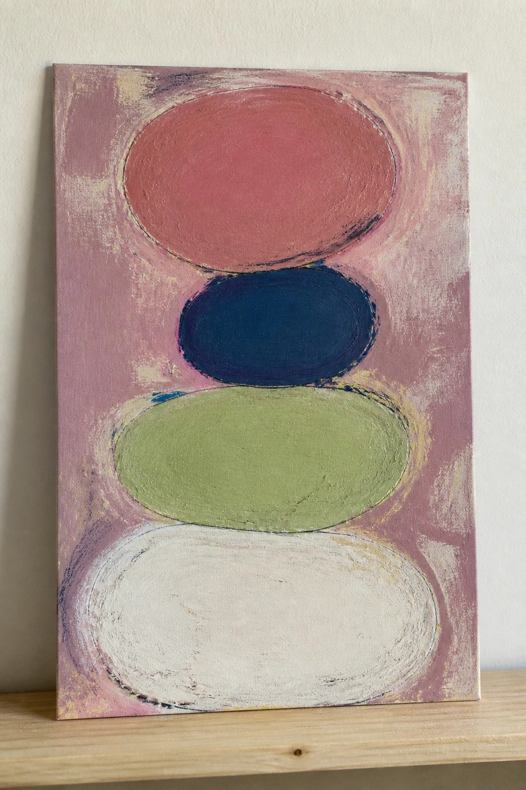 Abstract painting of four stacked ovals in red, blue, green, and white on pink background.