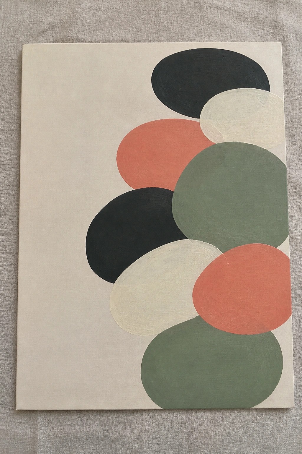 Abstract painting of overlapping ovals in black, coral, green, and cream on beige canvas.
