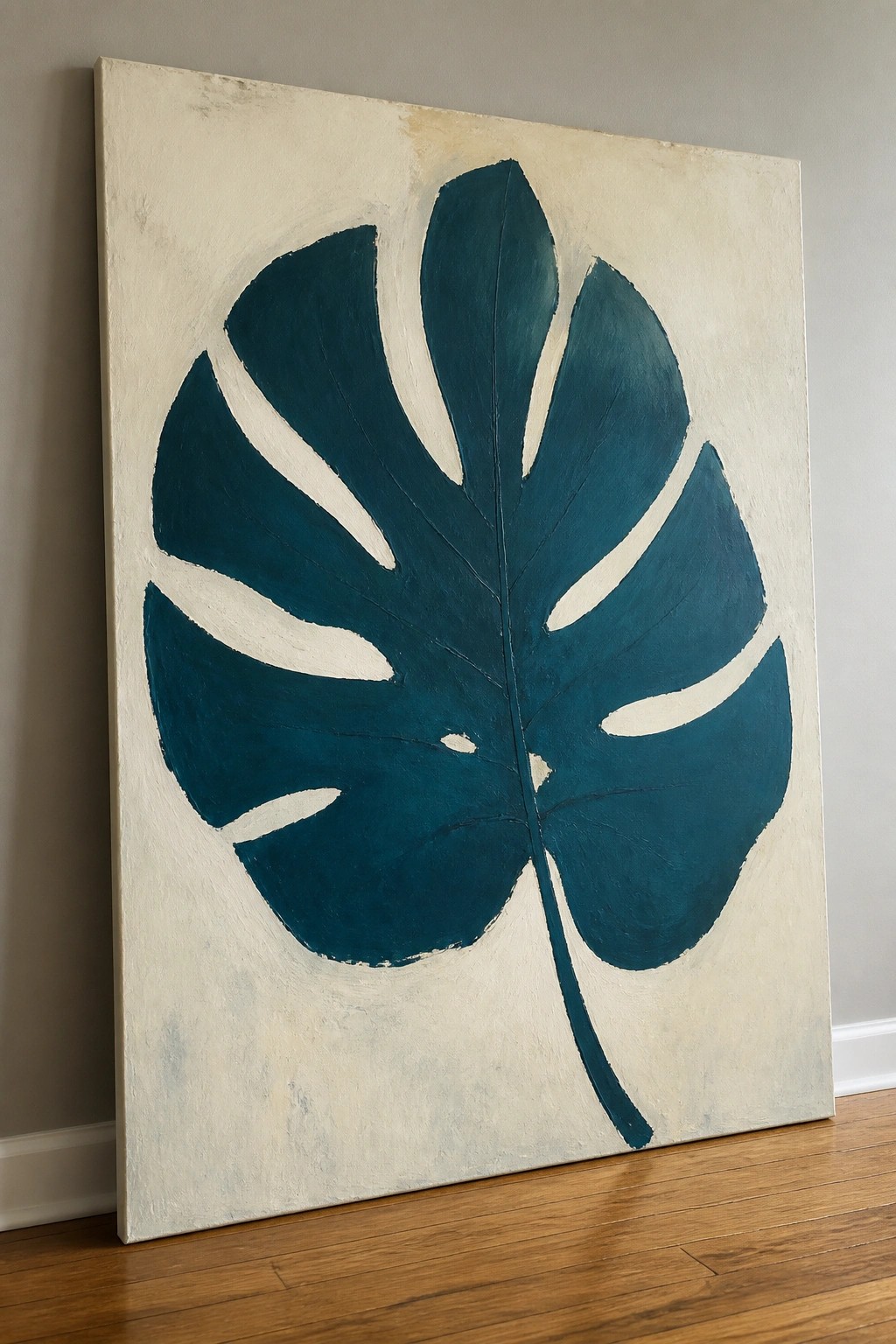 Large teal monstera leaf painting on off-white canvas against wall