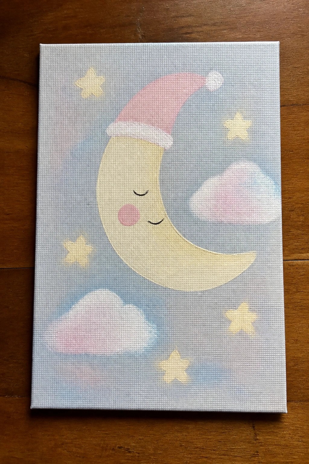 Cute smiling crescent moon in pink Santa hat with yellow stars and pink clouds on canvas