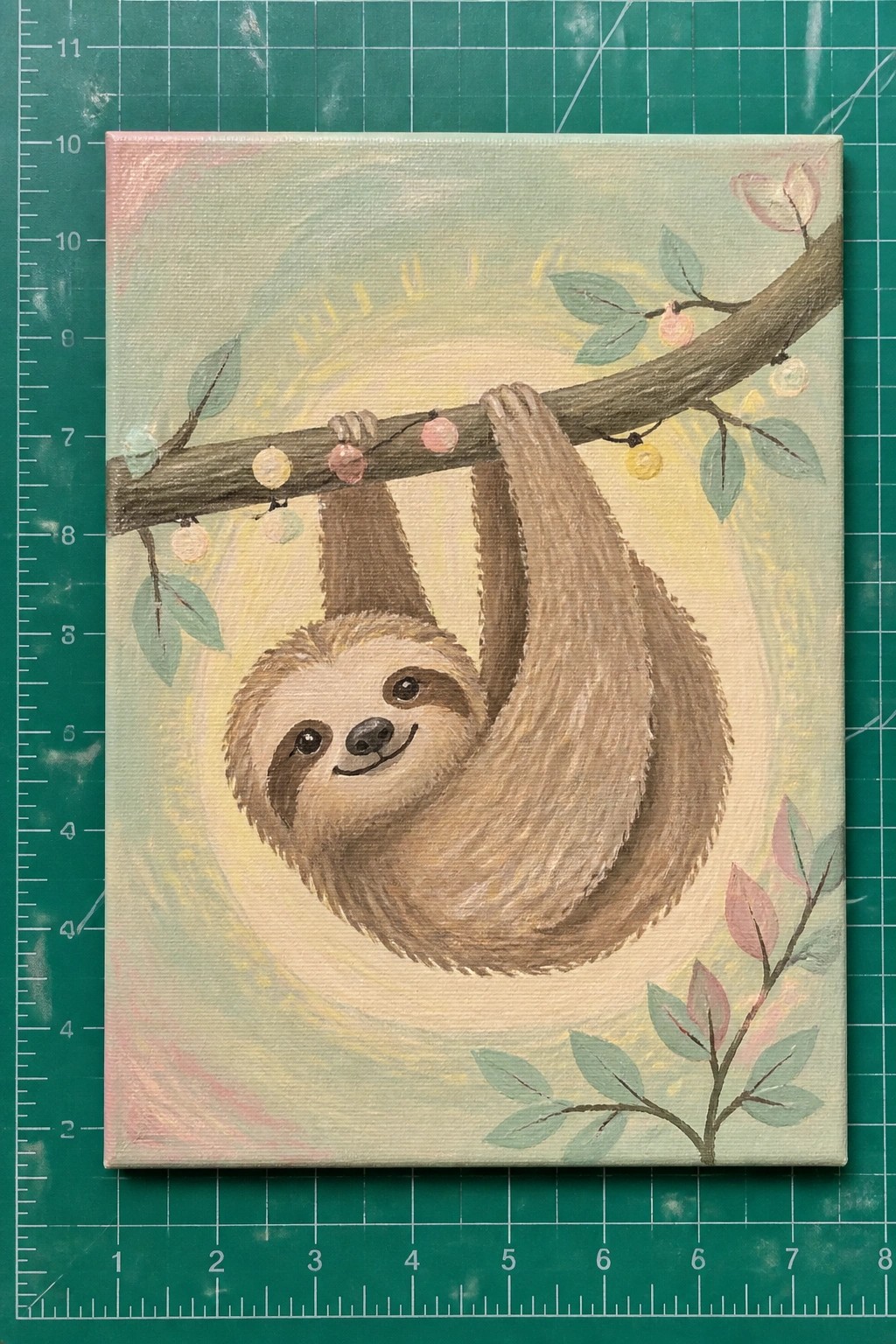 A painted canvas showing a brown sloth hanging from a branch with pastel string lights and leaves on a soft background.