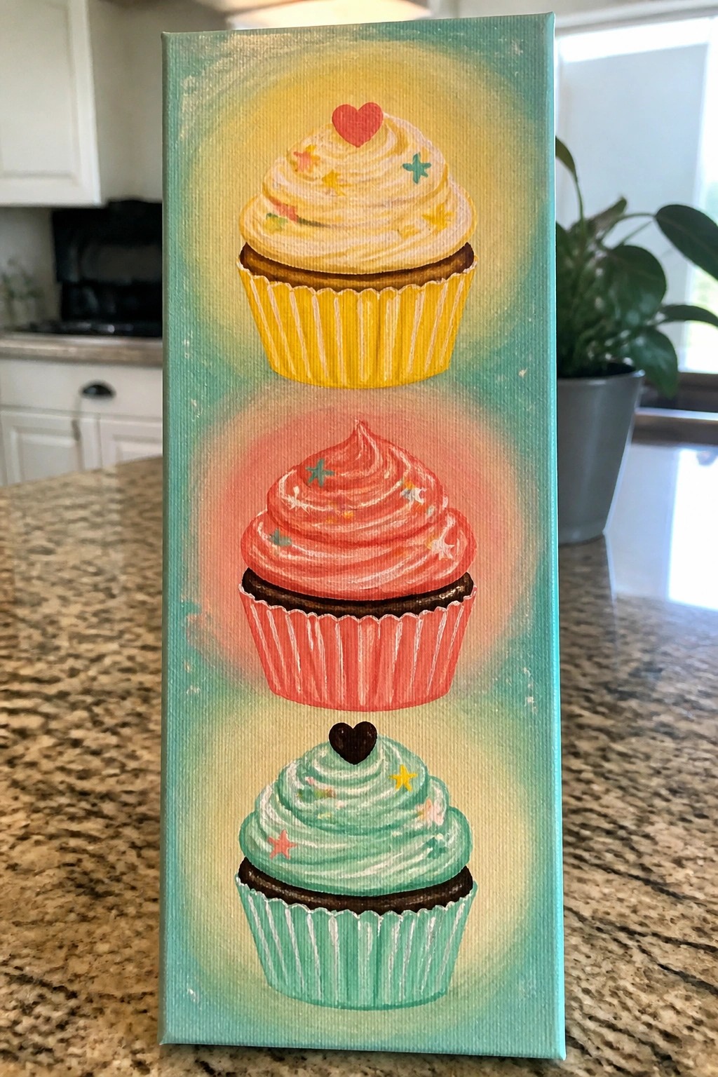 Vertical painting of three stacked cupcakes with yellow, pink, and mint frosting