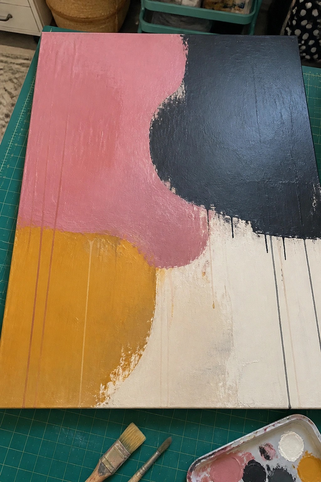 Abstract painting on canvas with pink, yellow, black, white shapes and drips.