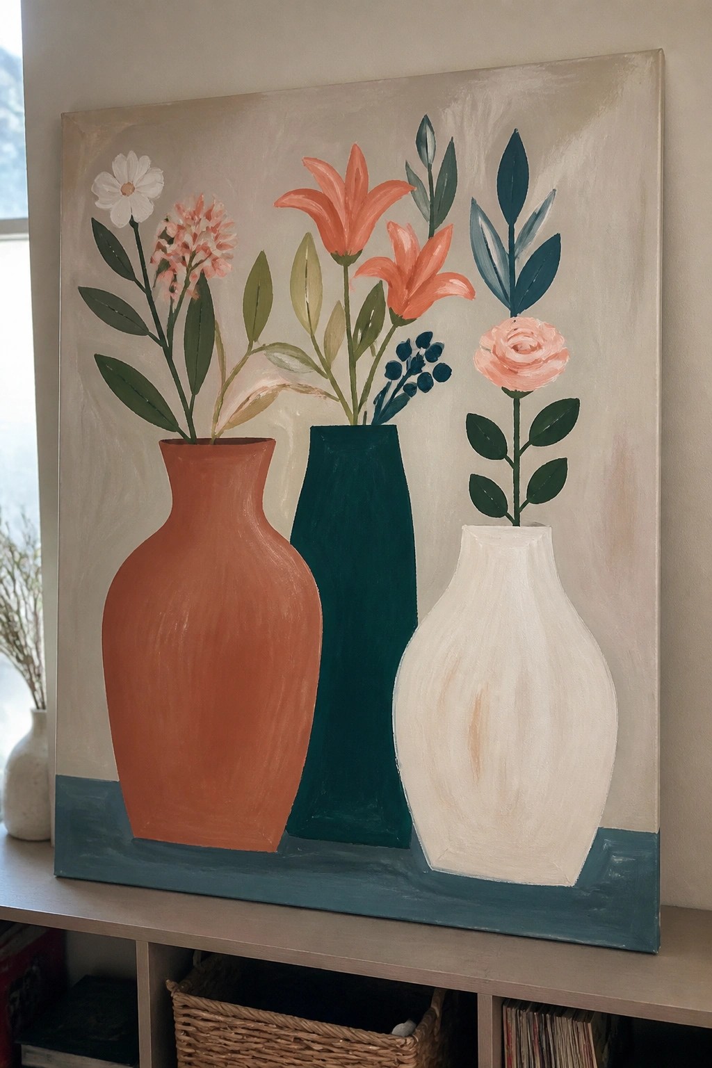 Three vases in orange, teal, and white with colorful flowers on blue surface.
