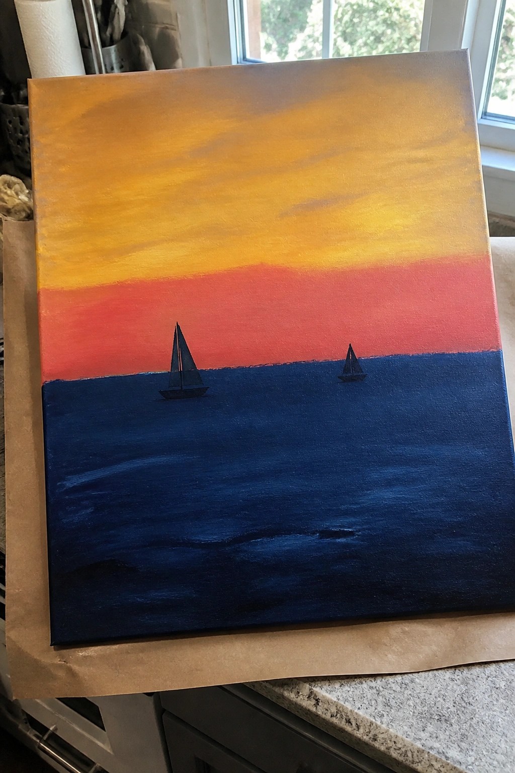 Sunset painting with yellow-orange-red sky above dark blue sea and two sailboats