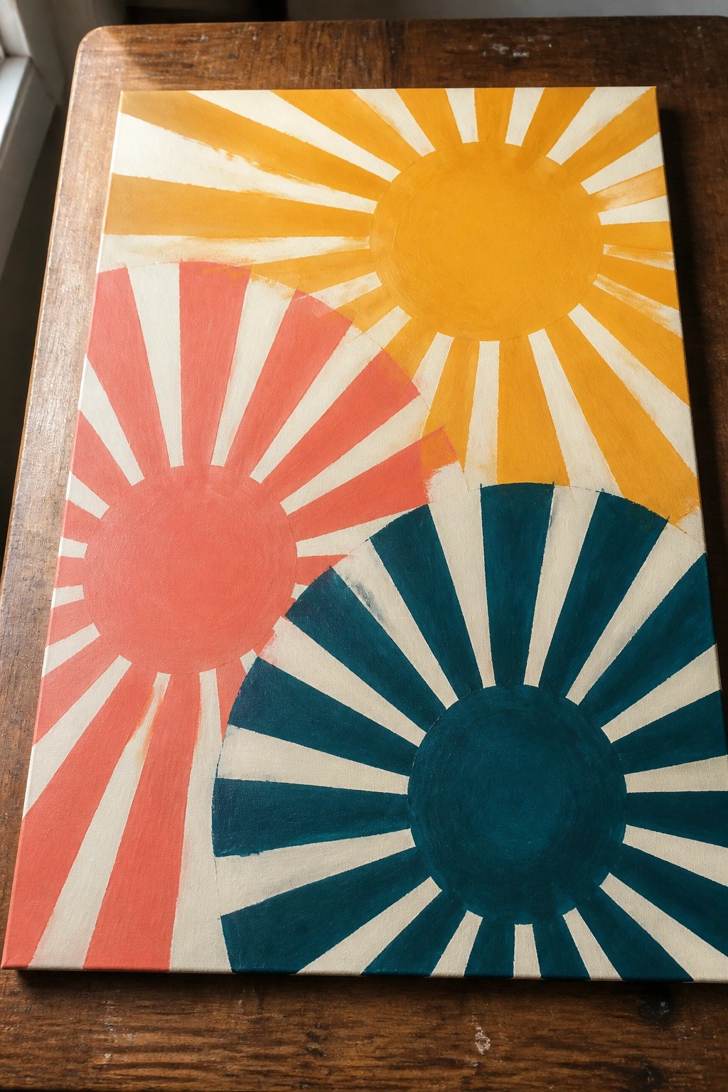 Abstract painting of three colorful sunbursts in yellow, red, and teal on white.
