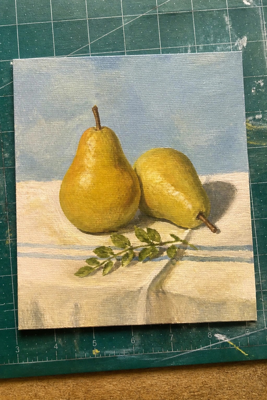 Two yellow pears with stems and leaves on white surface under blue sky painting