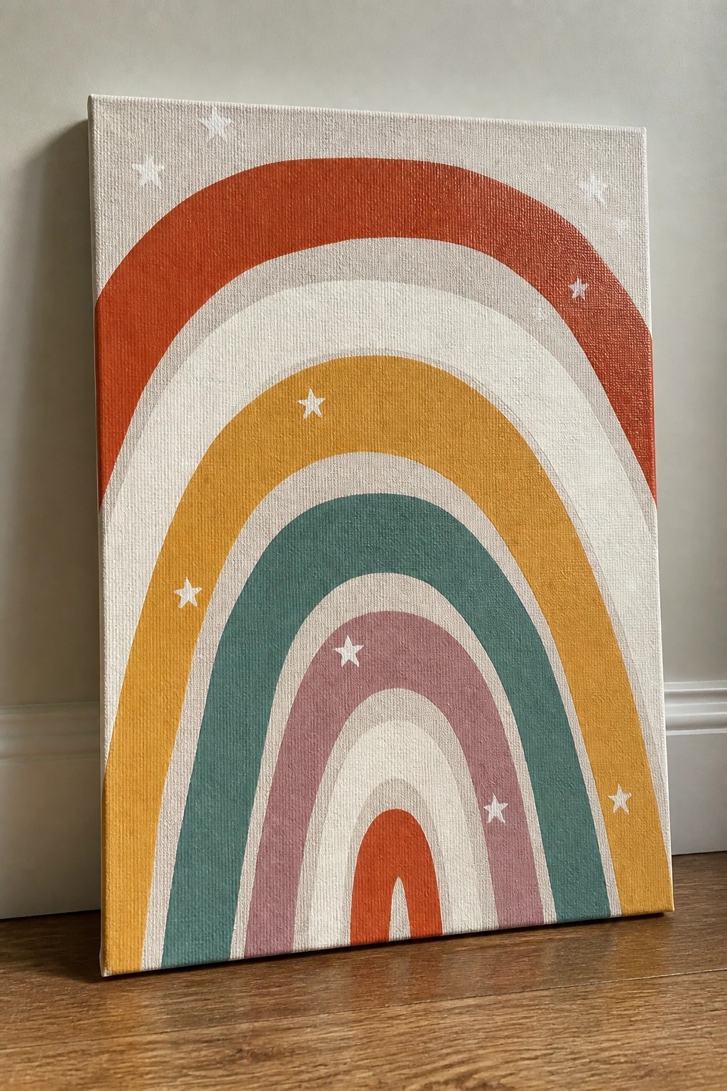 Colorful rainbow canvas with orange, yellow, teal, and pink arches plus white stars, leaning on floor