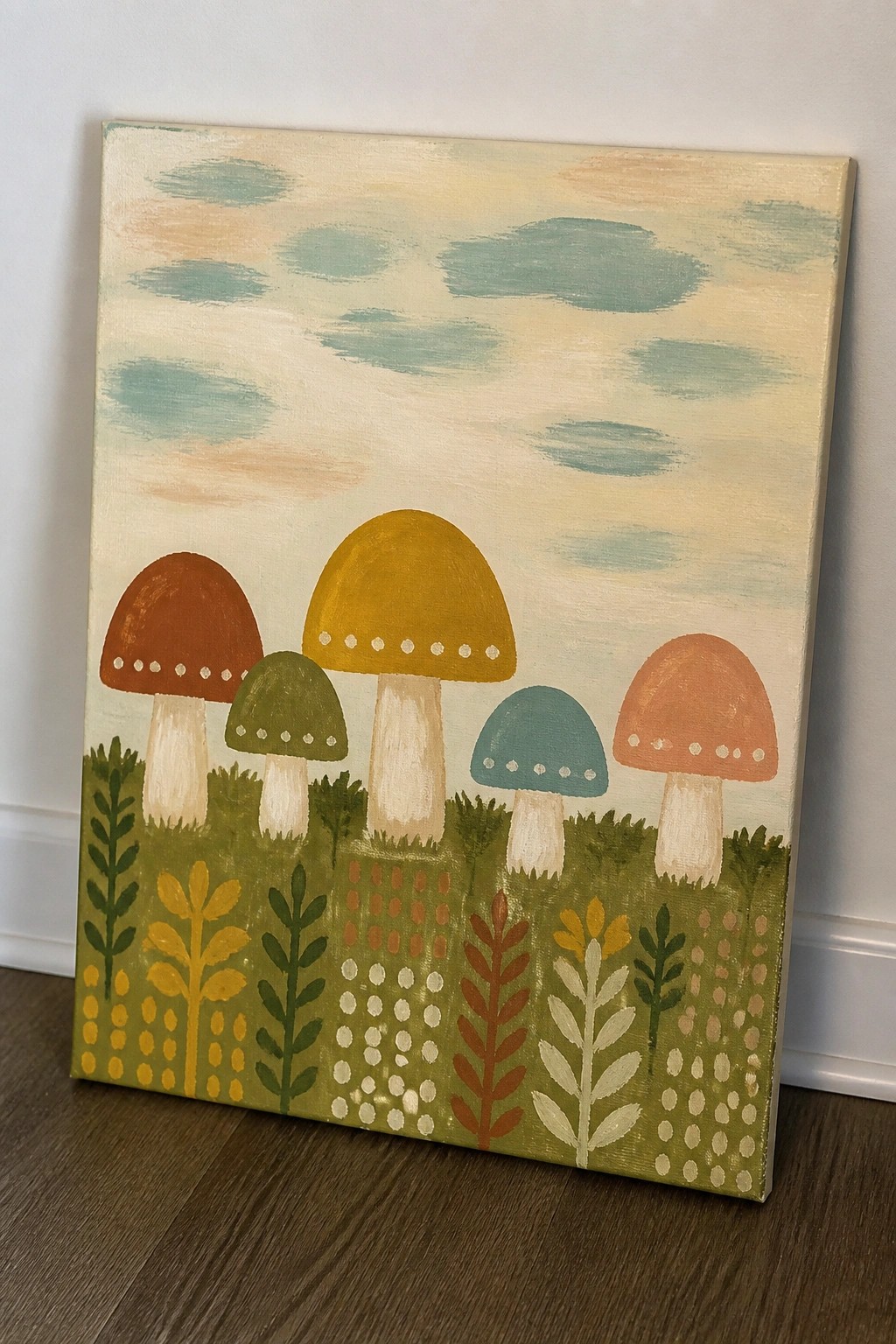 Colorful folk-art painting of five mushrooms in a patterned grassy field under clouds